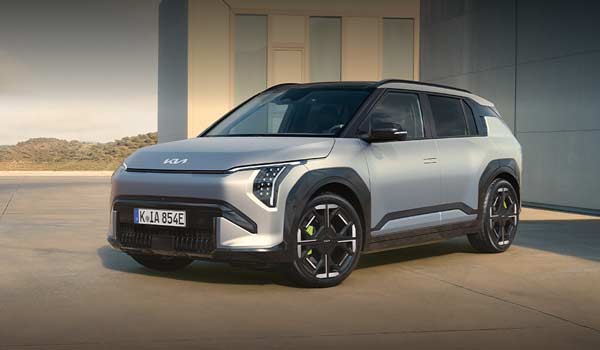 Kia yksityisleasing 8 Hopeinen Kia EV3 viistosti parkissa. Taustalla valkoinen rakennus sekä vihreä kumpuinen maasto.