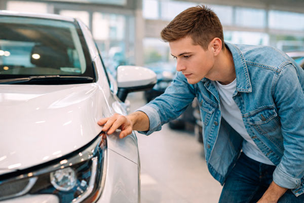 nuori mies katsoo autoa. AI:n luoma kuva.