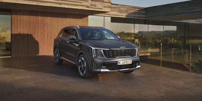 Kia Sorento Phev 2025 modernin talon edessä auringonlaskussa.